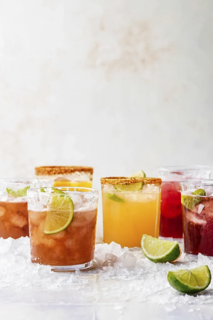 Gourmet cocktails with lime garnish and textured rims on crushed ice.