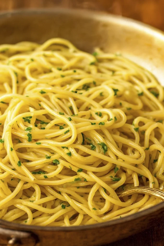 Golden spaghetti with butter and herbs served in a rustic pan.