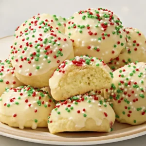 Italian ricotta cookies with glaze and Christmas sprinkles on a ceramic plate