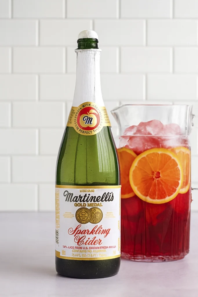 Red fruit punch with orange slices, cherries, and gummy bears in a glass and pitcher.