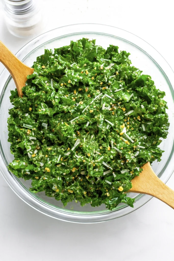 Plant-based kale salad with cheese and seeds in a clear bowl.