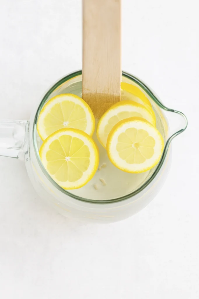 Lemon water recipe with lemon slices and wooden stirrer