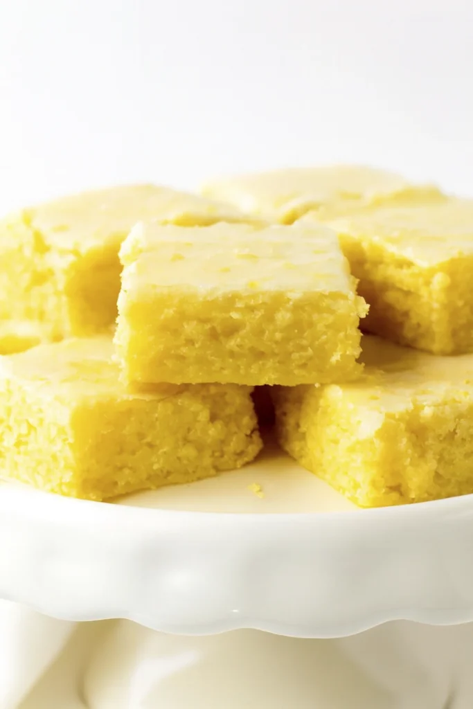 Overhead shot of lemon bars on parchment paper with lemon slices and mint garnish.
