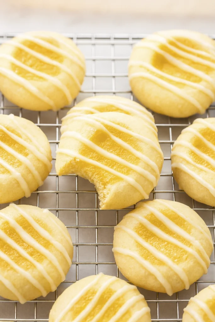 Lemon thumbprint cookies cooling on rack with icing drizzle