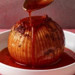 Roasted onion with caramelized grill marks drizzled with savory sauce in a white bowl.