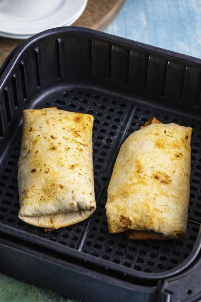 Golden brown cheeseburger wraps cooking in air fryer basket