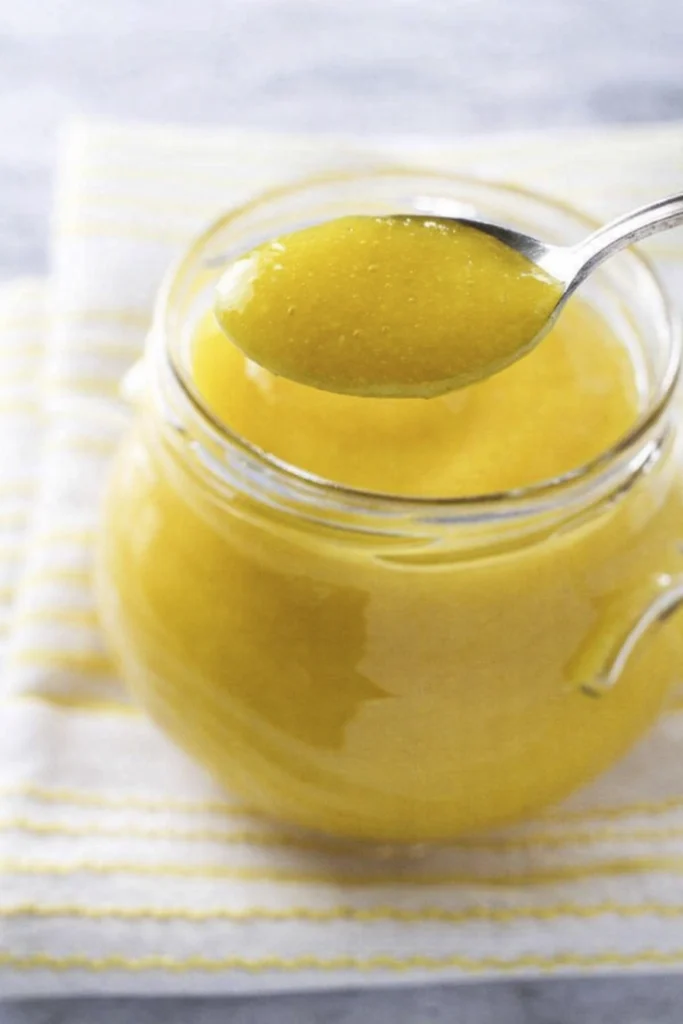 Spoonful of mango puree lifted from glass jar