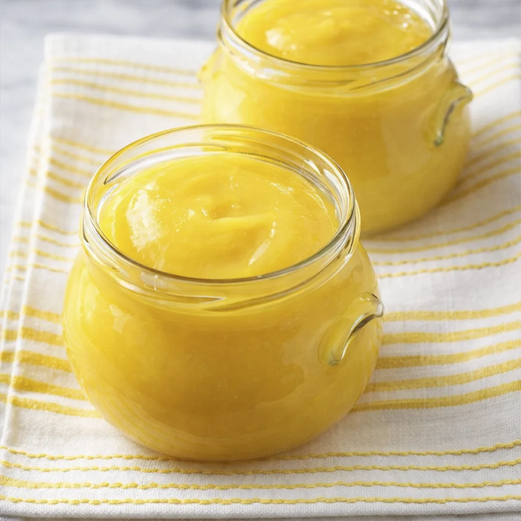 Homemade mango puree stored in glass jars on striped cloth
