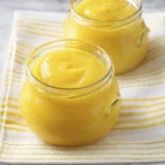 Homemade mango puree stored in glass jars on striped cloth
